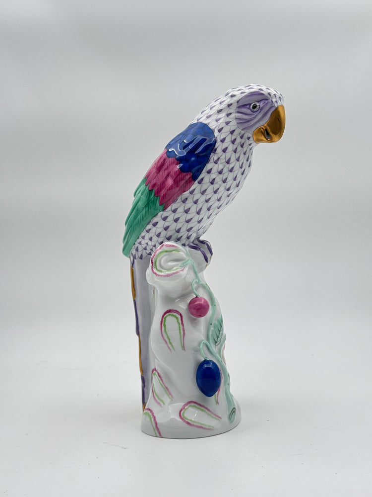 Herend hand-painted porcelain parrot figurine with purple fishnet pattern, gold beak, and colorful wings on a decorative white base.