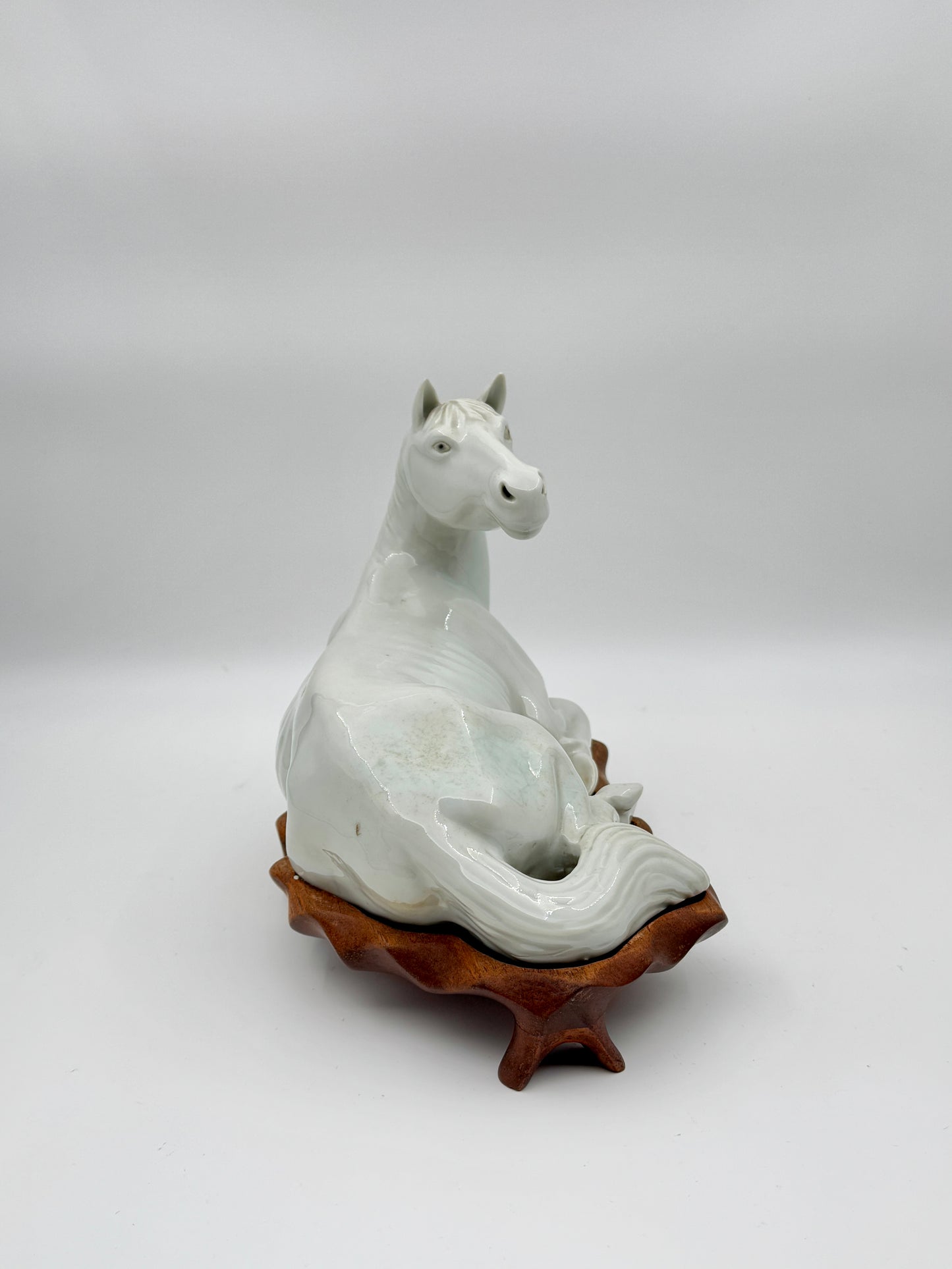 Pair of Chinese Blanc de Chine Porcelain Recumbent Horses on Carved Wood Stands