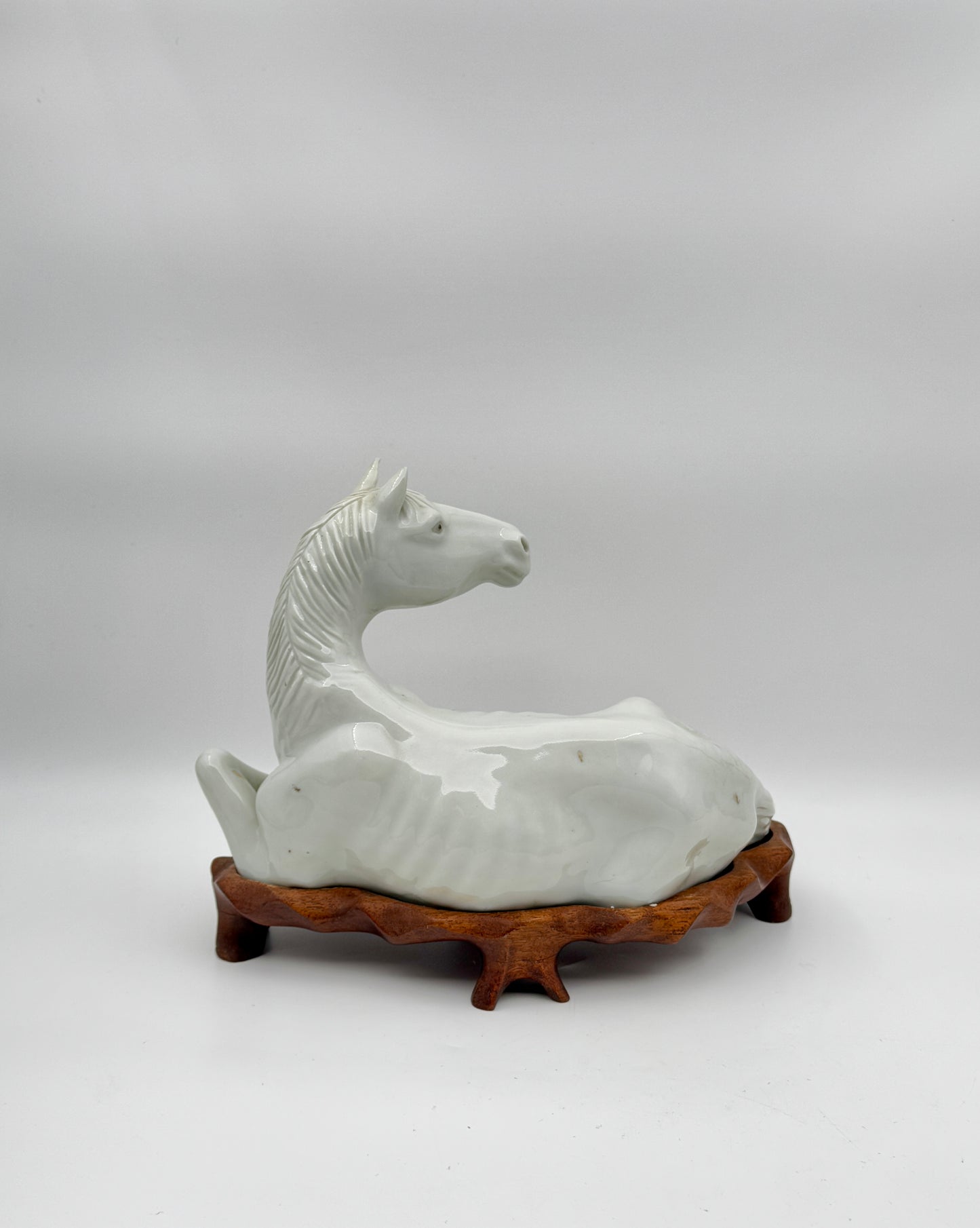 Pair of Chinese Blanc de Chine Porcelain Recumbent Horses on Carved Wood Stands