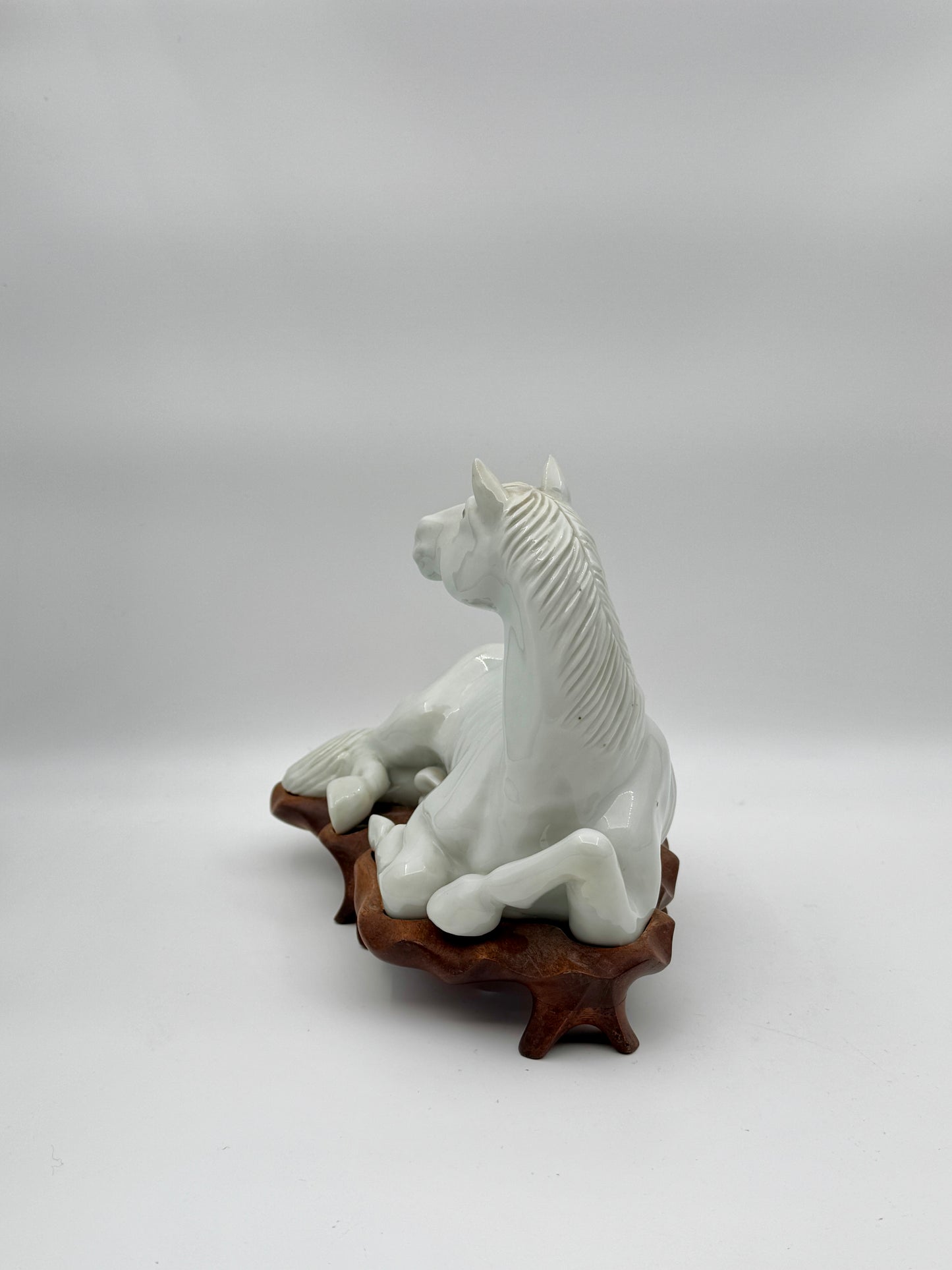 Pair of Chinese Blanc de Chine Porcelain Recumbent Horses on Carved Wood Stands