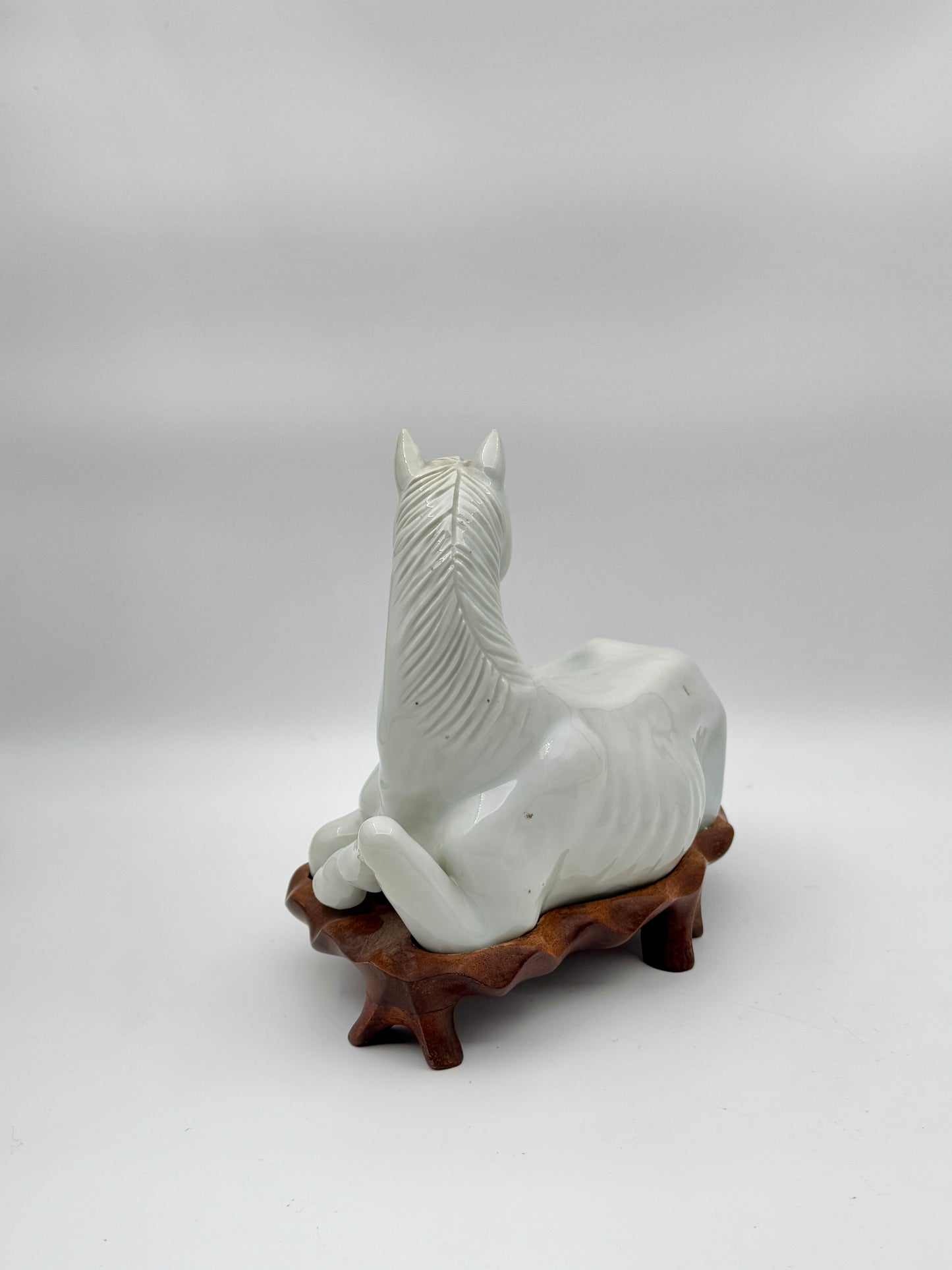 Pair of Chinese Blanc de Chine Porcelain Recumbent Horses on Carved Wood Stands