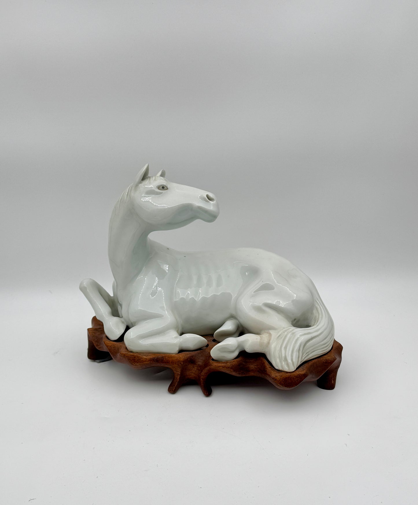 Pair of Chinese Blanc de Chine Porcelain Recumbent Horses on Carved Wood Stands