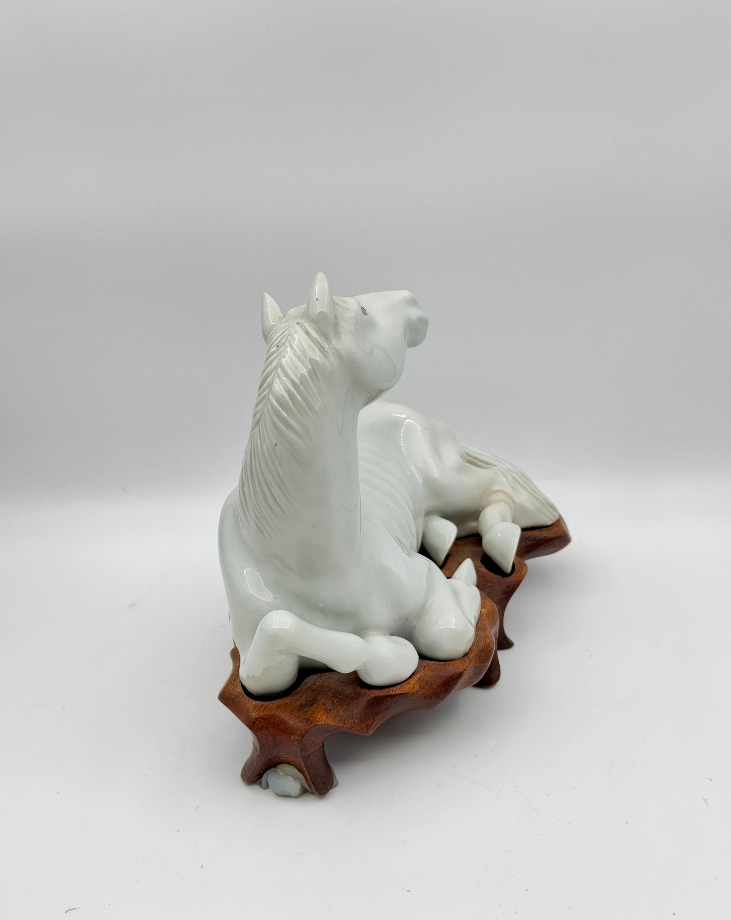 Pair of Chinese Blanc de Chine Porcelain Recumbent Horses on Carved Wood Stands