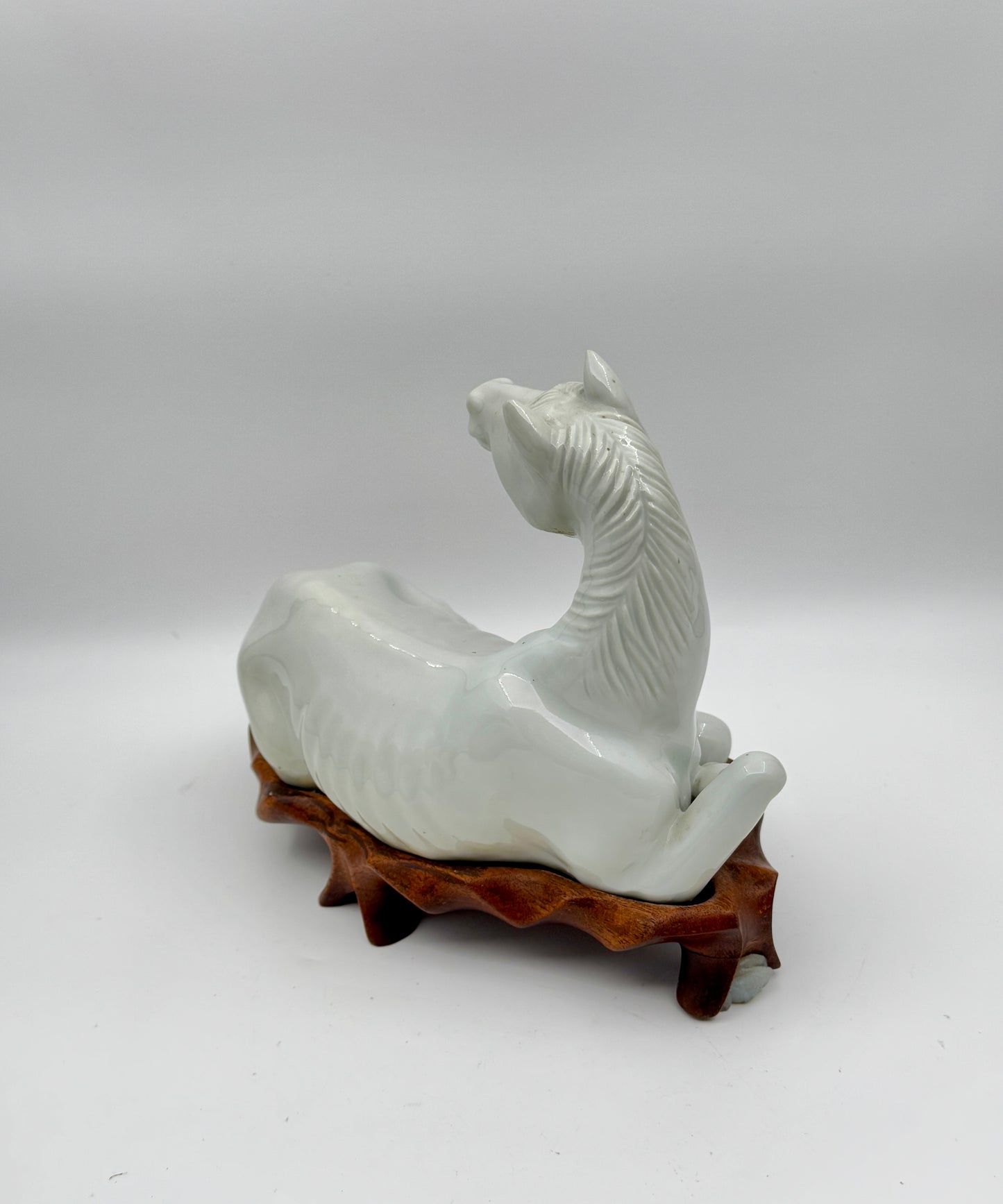 Pair of Chinese Blanc de Chine Porcelain Recumbent Horses on Carved Wood Stands