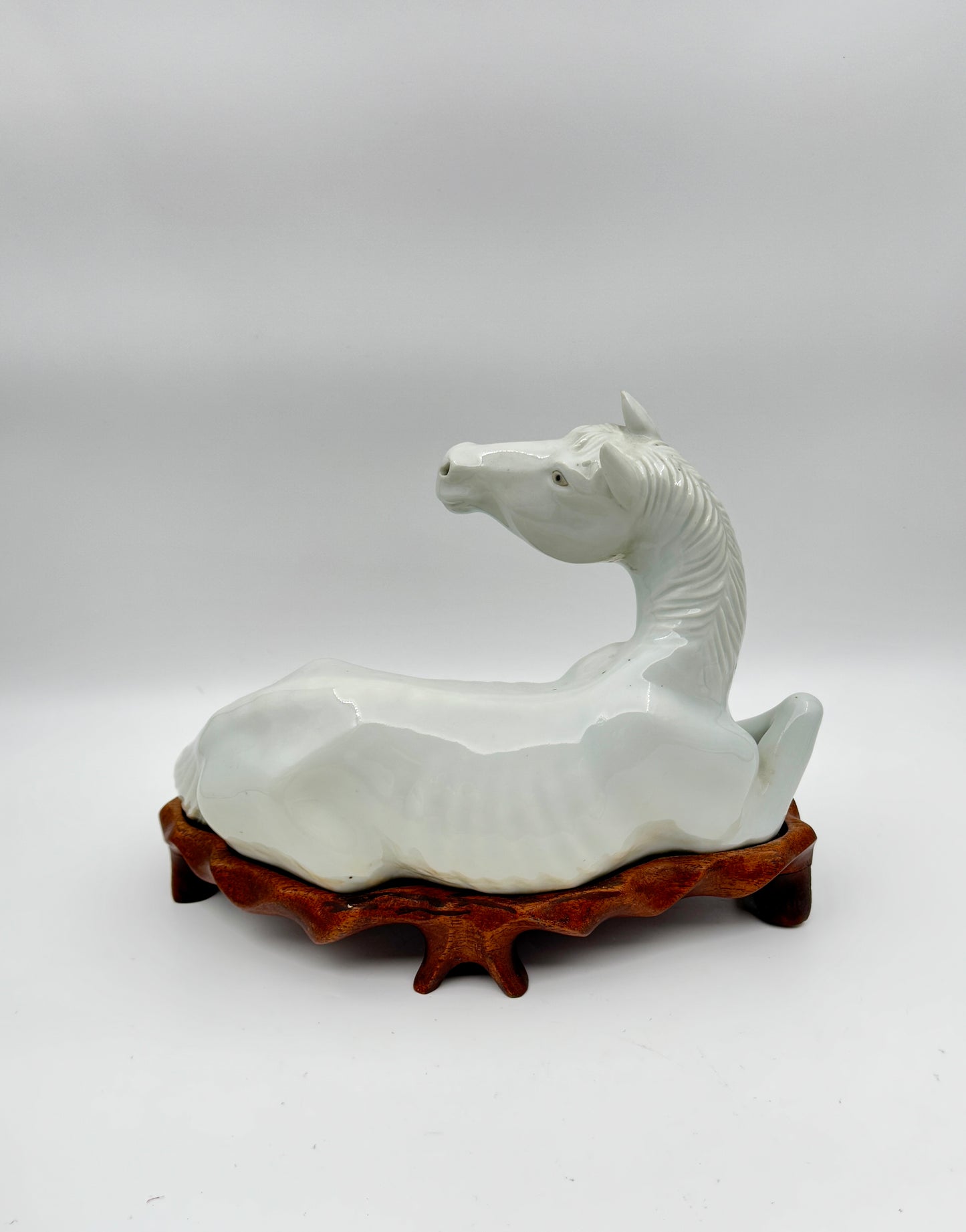 Pair of Chinese Blanc de Chine Porcelain Recumbent Horses on Carved Wood Stands