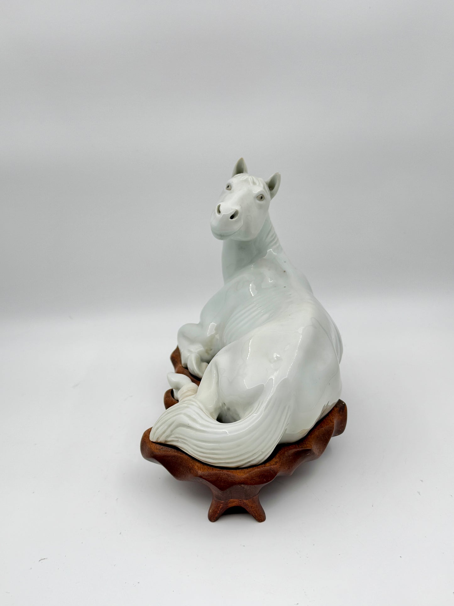 Pair of Chinese Blanc de Chine Porcelain Recumbent Horses on Carved Wood Stands